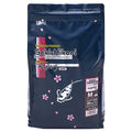 A bag of Saki-Hikari Koi Broke Flavored Advanced Diet for koi, in size M (20L). The packaging is dark navy blue with pink cherry blossom graphics, a white fish silhouette, and a red vertical accent bar on the left.
